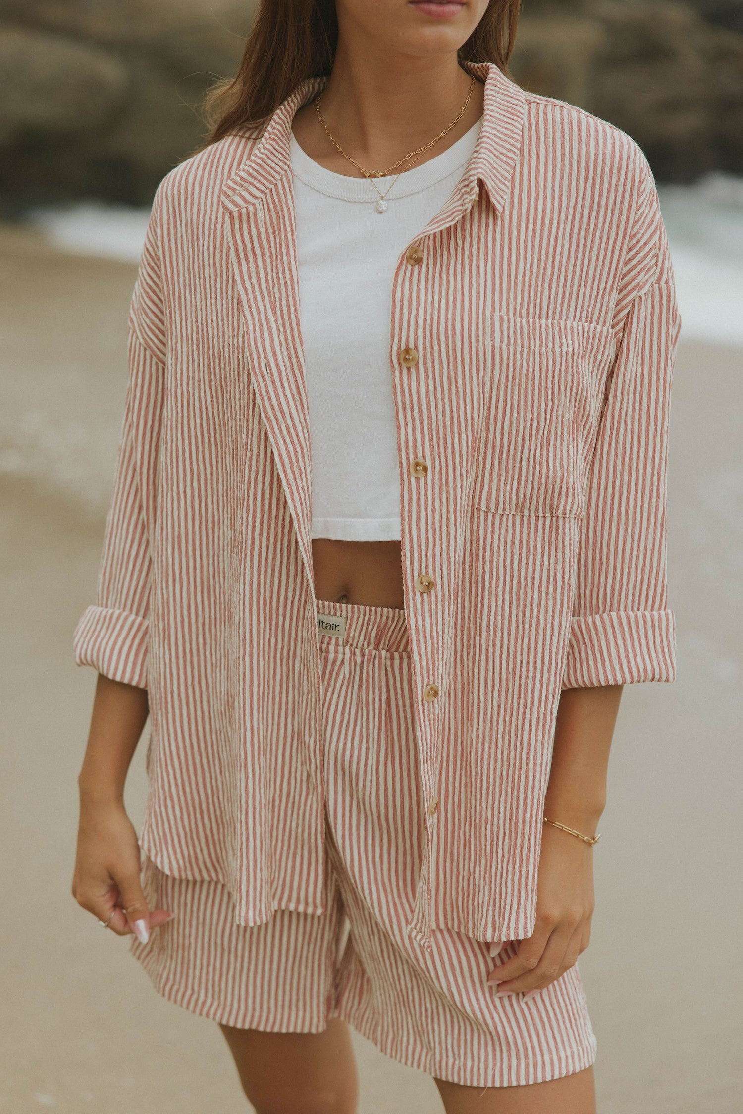 Striped long sleeve matching shorts and top beachwear set for women.
